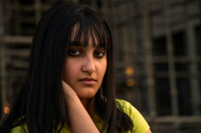 a woman with long black hair wearing a yellow shirt