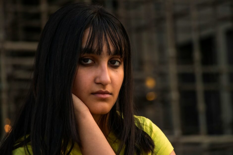 a woman with long black hair wearing a yellow shirt